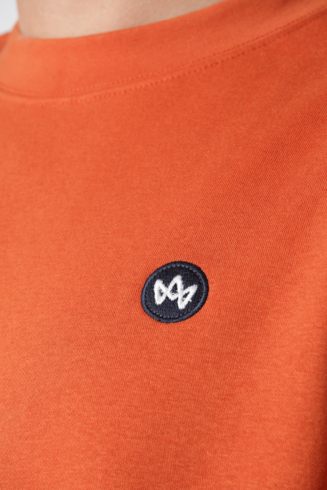 Sweatshirt Kronstadt i Burnt Ochre med lille farverigt broderi på brystet som diskret grafisk detalje.